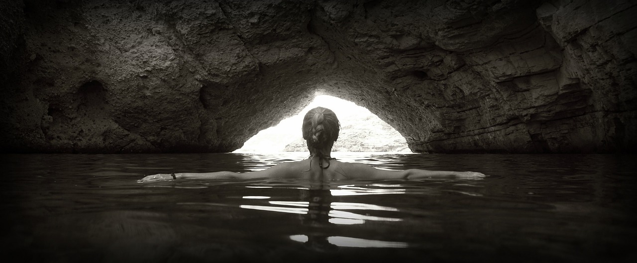 Woman swimming in a beautiful ocean side cave